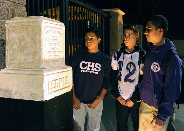 Cathedral High School students look at one of the tombstones lit up along the perimeter of the football stadium before last Friday night's game.  
