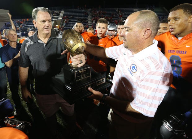 AIA Executive Director Harold Slemmer (left) presents the Sollenberger Classic trophy to Bishop Gorman coach Tony Sanchez.