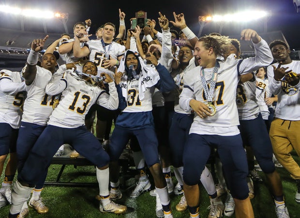 St. Thomas Aquinas players celebrate while hoisting the championship trophy.