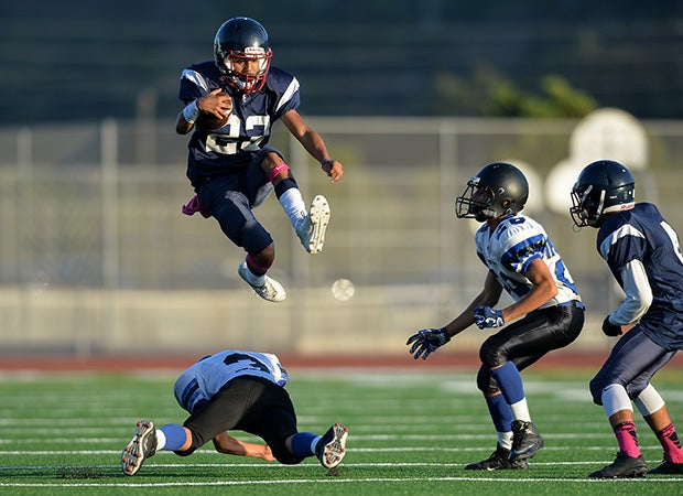 A Steele Canyon (Calif.) running back leaps over a West Hills defender during a freshman game.