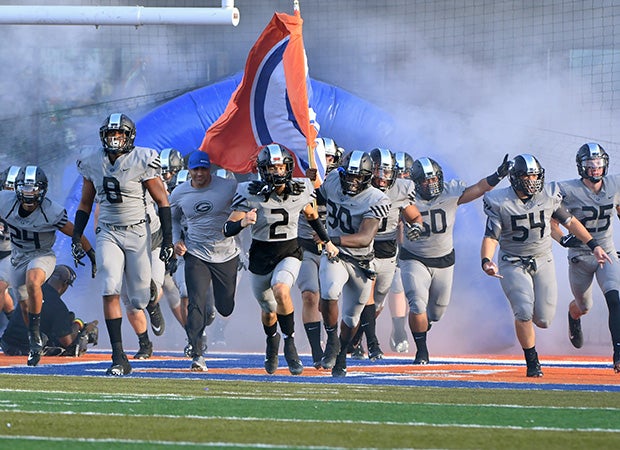 Head coach Kenny Sanchez and his players rush onto the field in pre-game ceremonies.