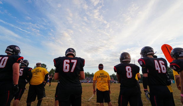 The Chopticon staff, donning their Touchdowns Against Cancer shirts, and players look on during the Leonardtown game.