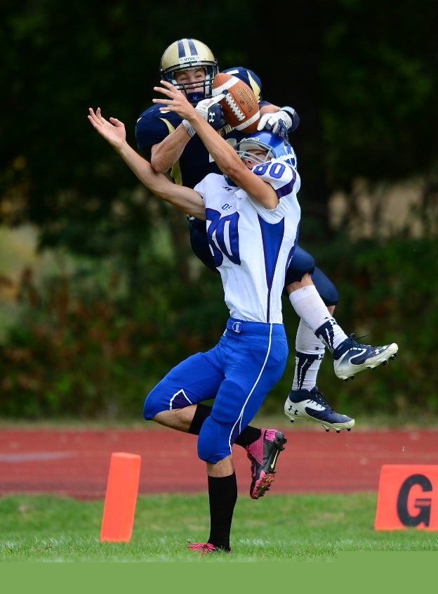 A player from Old Saybrook-Westbrook (Conn.) goes for the ball while a Hyde Leadership (Hamden, Conn.) leaps over him.