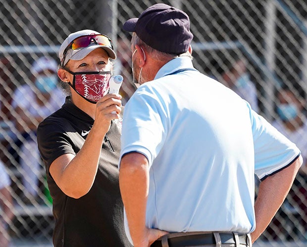 Chatfield (Colo.) varsity softball coach Jen Lazzeri checks the temperature of an umpire before their home game against Ralston Valley during the COVID-19 pandemic.