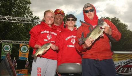 Hinsdale Central High School’s (from L to R) Abbey King, head coach Bob Barber, Austin Laniosz and Brent Phillip show off a pair of bass prior to weighing in their fish at the IHSA Bass Fishing State Finals.
