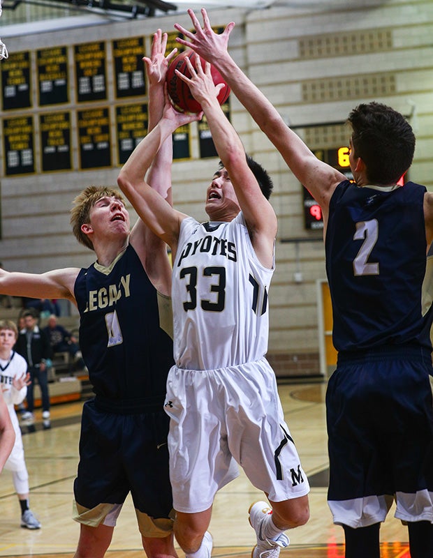 Monarch (Colo.) guard Tylor Trinh takes a jump shot between two Legacy defenders.