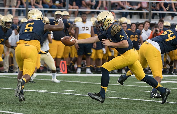 Aquinas quarterback Curt Casteel hands off to running back Daniel Carter.