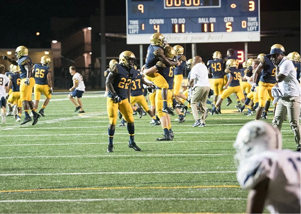 St. Thomas Aquinas players and coaches celebrate following their 9-3 victory over St. John Bosco on Friday night.