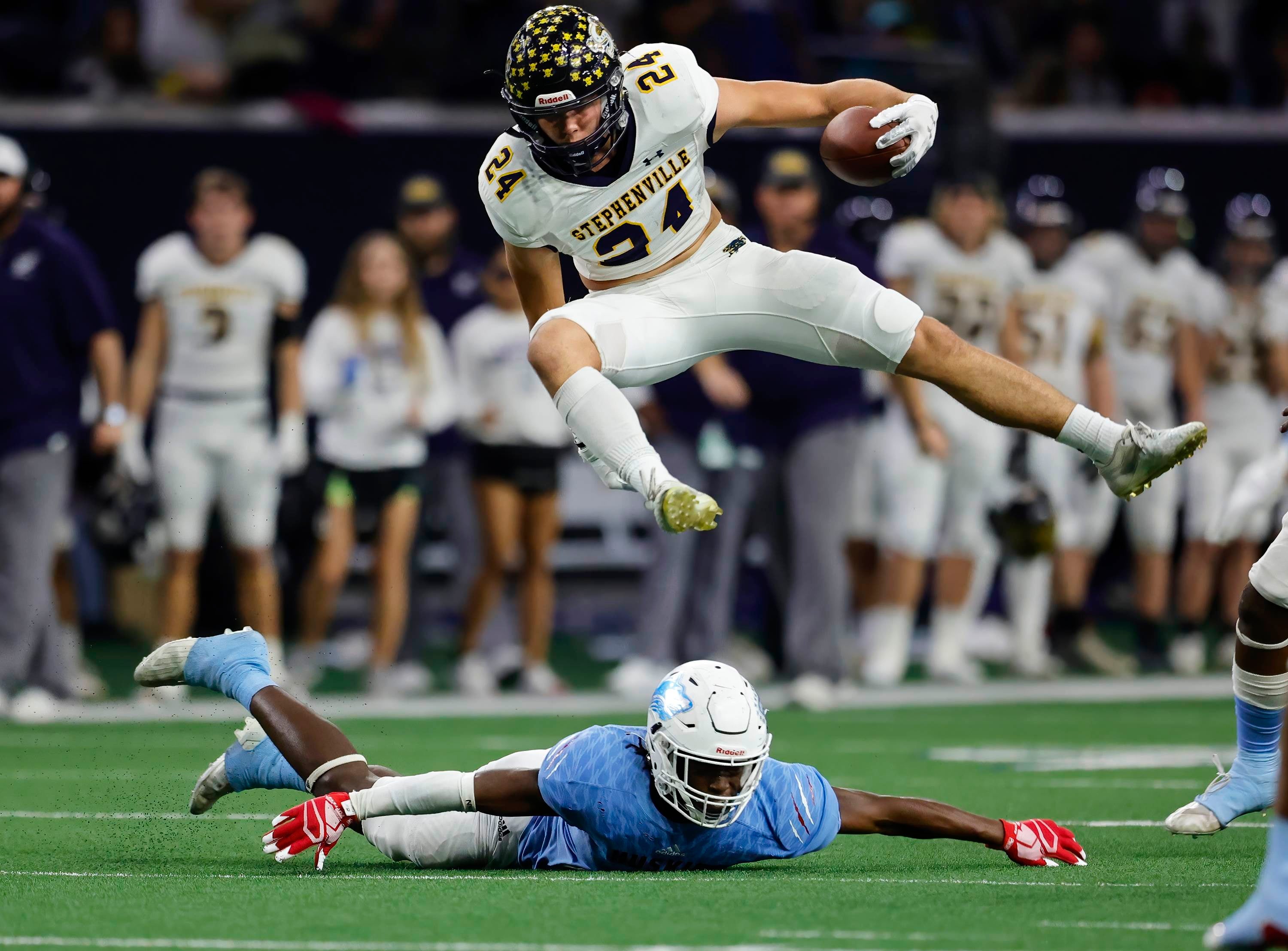 Stephenville's Reece Elston leaps over would-be tackler Keyshun Jackson of Hirschi during the Texas football postseason.