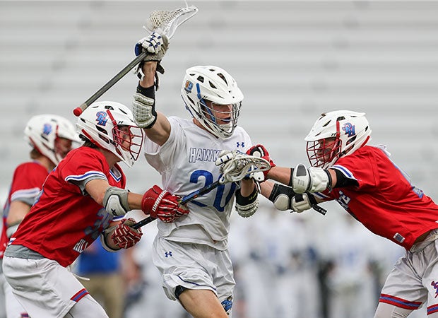Rockhurst (Mo.) midfielder Luke Looney powers through two Pembroke Hill lacrosse defenders while keeping control of the ball.