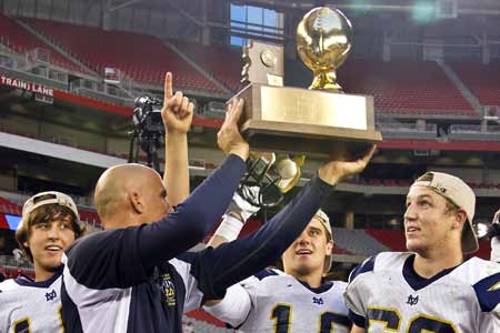 Desert Vista coach Dan Hinds holds up the Division I championship trophy at University of Phoenix Stadium.