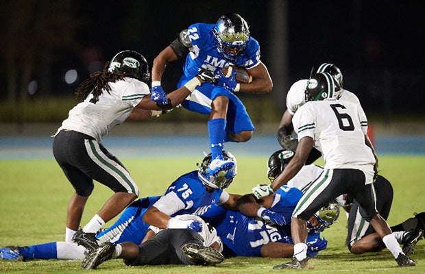 Noah Cain of IMG Academy leaps over a pile of players while attempting to elude several Miami Central defenders.