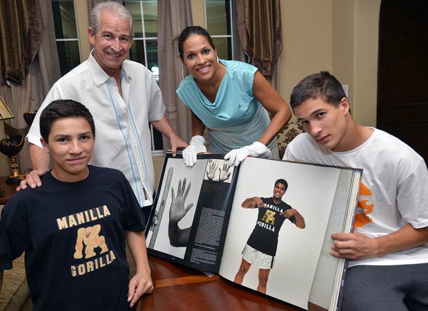 Biaggio Ali Walsh (right) with his brother, Nico, along with their father, Bob Walsh, and mother, Rasheda Ali-Walsh, look through a book highlighting the boxing career and life of family patriarch Muhammad Ali. Biaggio is a star freshman running back for Bishop Gorman in Las Vegas. 