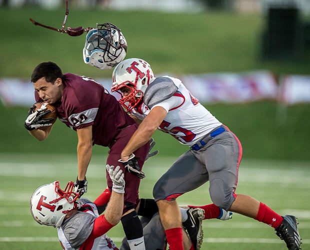 A Northbrook player's helmet is sent soaring while two Tomball defenders tackle him during an October game in Texas.