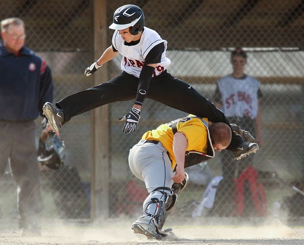 A St. Paul player leaps over a Monroeville catcher while trying to score during an Ohio junior varsity game in April.
