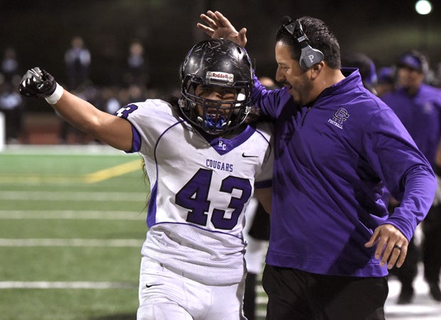 Rancho Cucamonga linebacker Samuel Malupo celebrates with a coach along the sideline.