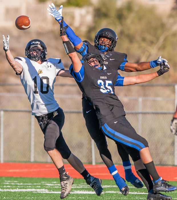Round Valley (Ariz.) receiver Calton Merrill (left) prepares to catch a touchdown pass behind two leaping Joy Christian defenders in an AIA Division 5 semifinal playoff game.