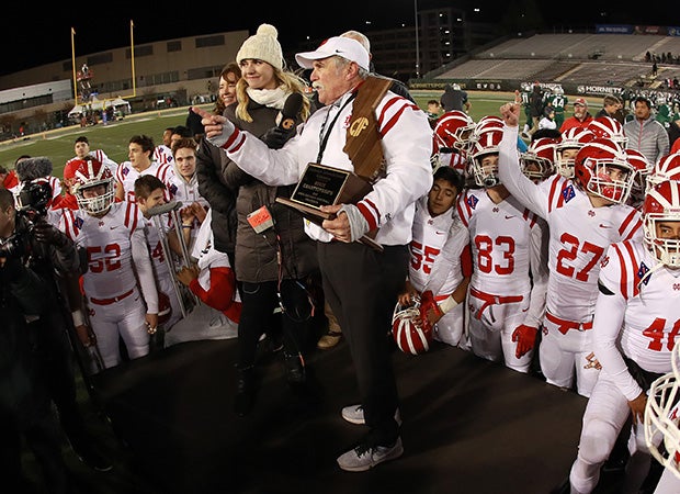 Mater Dei coach Bruce Rollinson is interviewed while holding the Open Division state championship trophy following the victory over De La Salle.