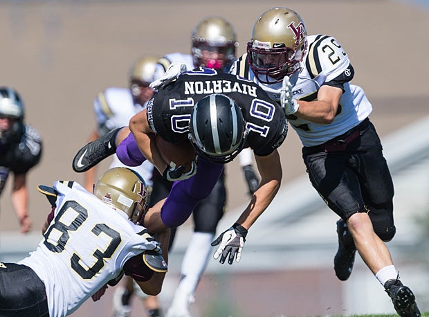 A Riverton (Utah) JV running back goes horizontal while being tackled by two Lone Peak (Highland, Utah) players.
