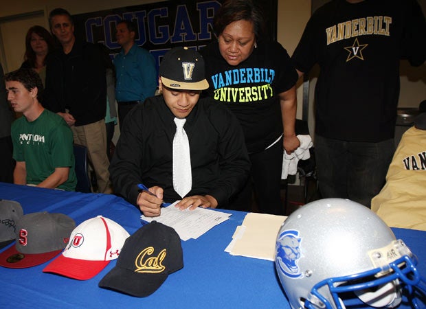 Nifae Lealao Jr. signs his letter of intent while his mother, Mary, looks on.