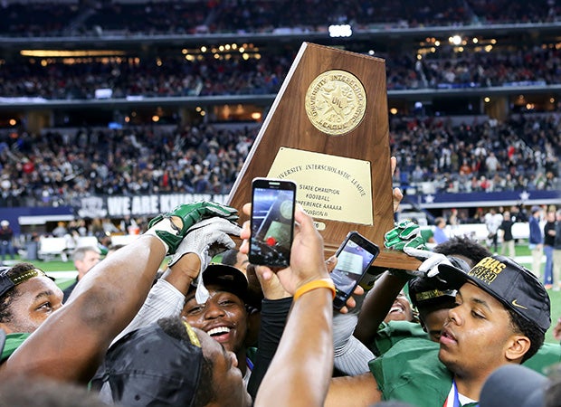 DeSoto players hoist the state championship trophy while taking cell phone photos.