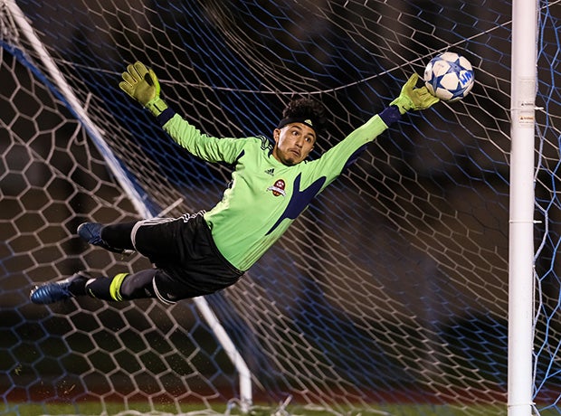 A James Logan (Calif.) goalie gets his fingers on a direct free kick by a Newark Memorial player.