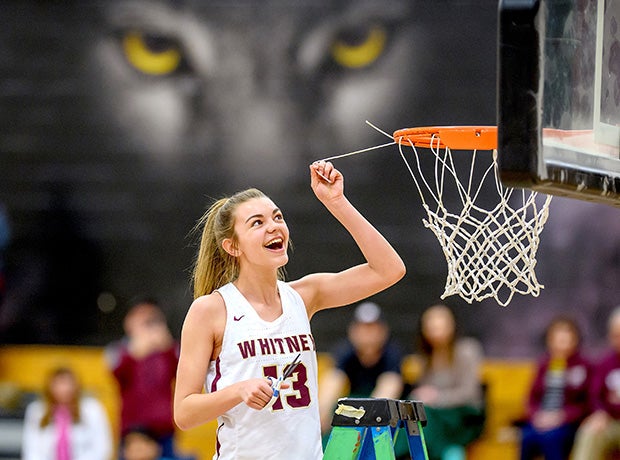 The Whitney (Calif.) mascot looks on as freshman Sophie Railsback cuts a piece of the net after the school's first league championship in girls basketball.