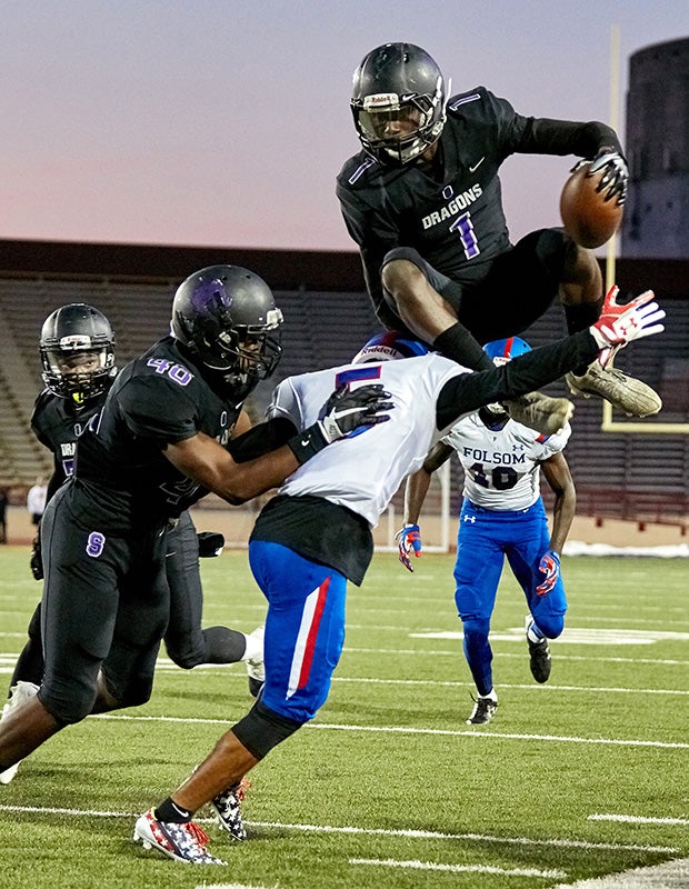 Sacramento (Calif.) receiver Anthony Bradley attempts to leap over a Folsom defender at Hughes Stadium.
