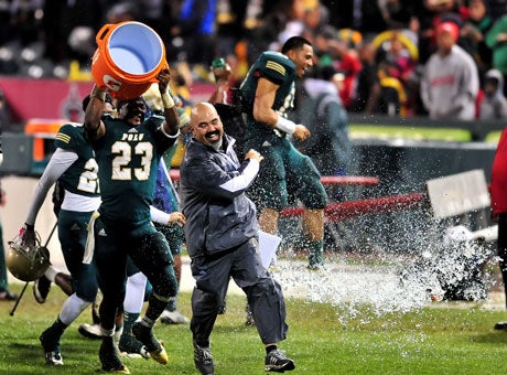 Running back Gerard Wicks douses coach Raul Lara with an icy bucket of celebration water after Long Beach Poly continued its postseason blitz with a triumph over Mater Dei in the Pac-5 title game.