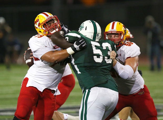 Oceanside's Robby Buckmire (53) fights through two offensive linemen. 