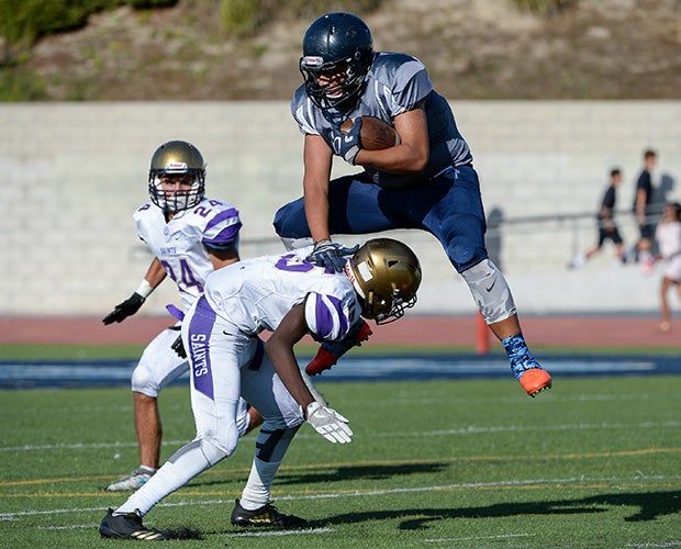 An Otay Ranch (Calif.) running back leaps over a St. Augustine defender during a junior varsity game.