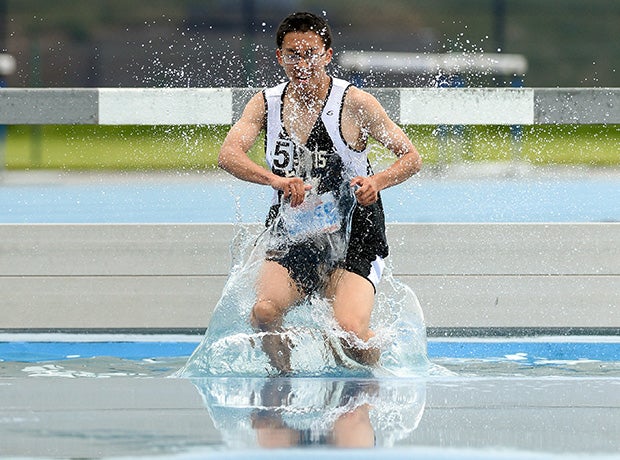 A Francis Lewis (N.Y.) runner splashes his way through the water hazard during the boys 3000-meter steeplechase at the PSAL Track and Field  Championships in New York.