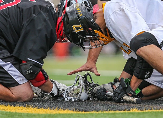 A St. John-Vianney player (right) and a Jackson Memorial player face-off as an official drops the ball during a boys lacrosse game in New Jersey.
