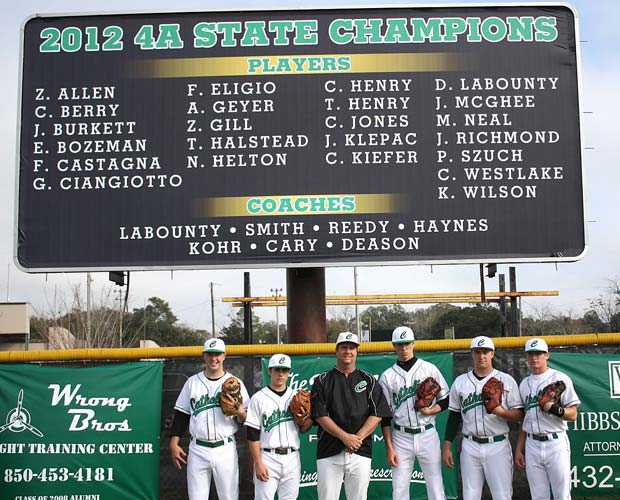 Head coach Richard LaBounty (in black jacket) poses with a few of his players in front of a newly installed billboard honoring last year's state championship team. 