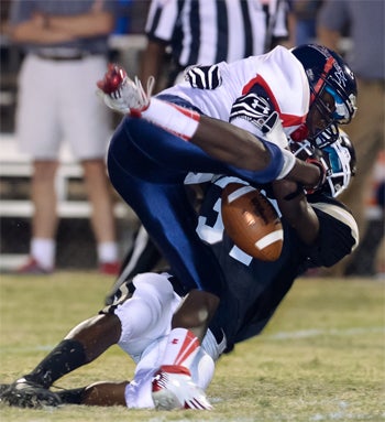 A Lugoff-Elgin Demon and Camden Bulldog fight for possessionof the football on Friday night's intense rivalry game.