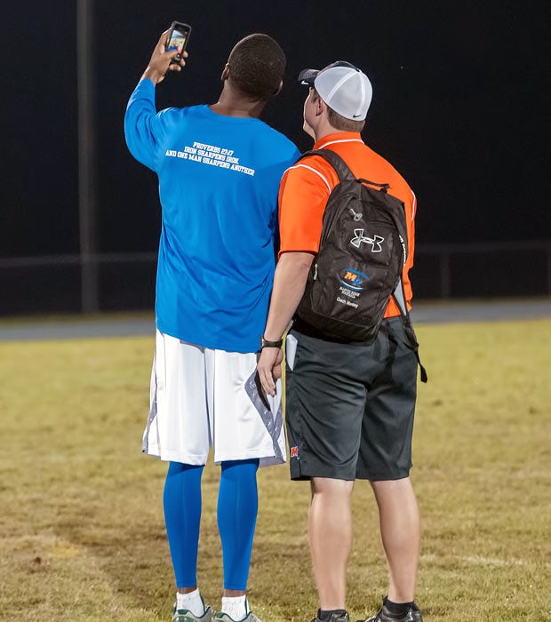 Randy Moss takes a "selfie" with a Marvin Ridge coach following the game.