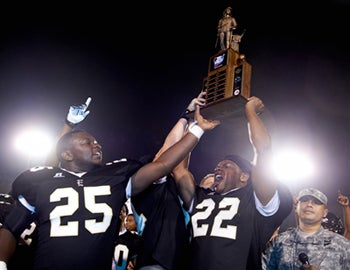 Junior Carlos Dorsey (25) and Senior Joacinto Grimes (22)
hoist the National Guard Rivalry trophy after their last
minute 26-21 victory over Lakeside.