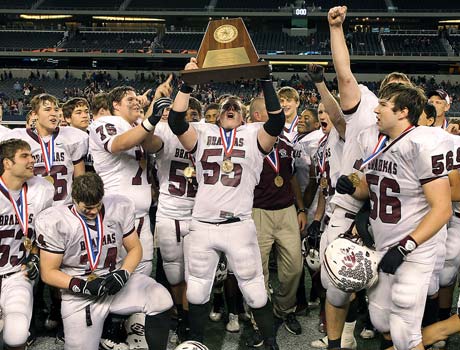 East Bernard players celebrate winning the Texas Class 2A Division II state championship by hoisting the trophy. 