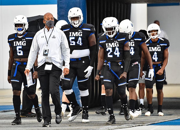 IMG head coach Bobby Acosta leads his team onto the homefield.