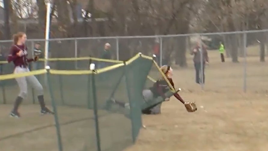 Taiylor Ellingson of Grand Forks Central (ND) somehow dives through the outfield fence and makes a spectacular grab